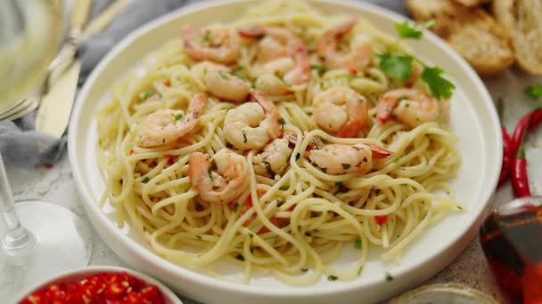 Špagety s krevetami na bílém keramickém talíři a podávané se sklenicí bílého vína — Stock video