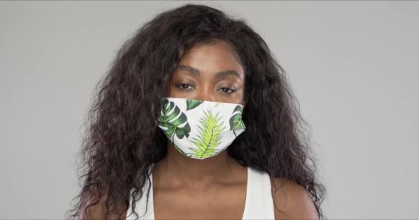 Afroamerikansk Kvinna Prydnadsduk Mask Tittar Kameran Epidemi Mot Grå Bakgrund — Stockvideo