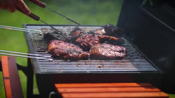 庭の炭火焼きにバーベキューリブをひっくり返す男おいしい食べ物の準備 — ストック動画