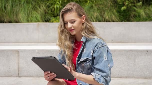 街中の石のベンチに座りながらノートを読みながら カジュアルな服装で若い女子学生の側面図 — ストック動画