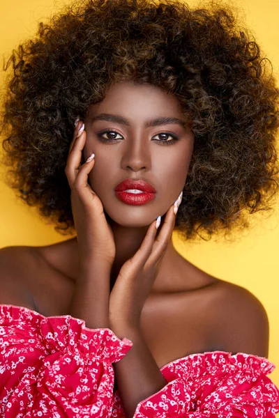 若いですアフリカ民族女性とともに巻き毛と赤口紅のタッチ顔とカメラを見て黄色の背景に孤立 — ストック写真
