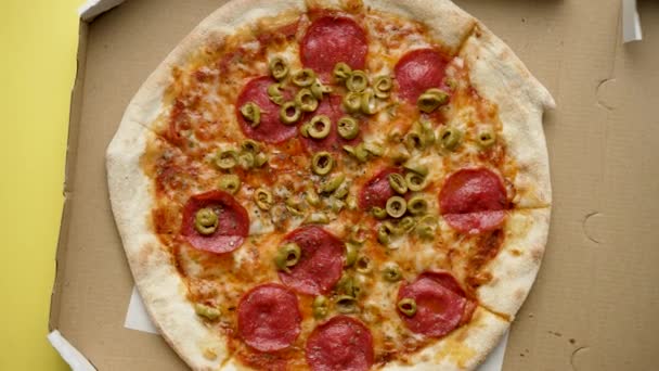 新鲜而热的比萨辣香肠在一个送货箱里 顶部视图 黄色背景 — 图库视频影像