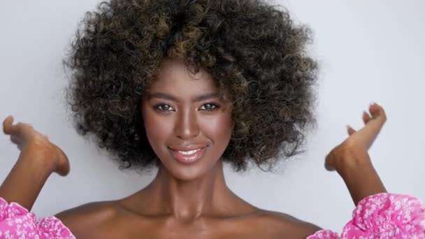 美丽的非洲裔女人在镜头前调整着她的发型 满脸笑容 赤手空拳 在自然背景下 — 图库视频影像