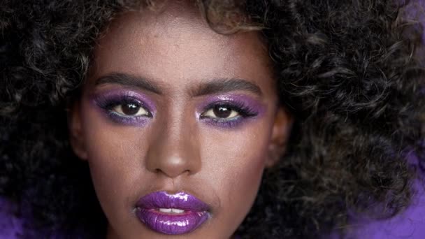 Закрыть Портрет Красивой Африканской Модели Афроволосами Идеальным Сияющим Фиолетовым Макияжем — стоковое видео