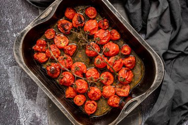 Tray of roasted red cherry tomatoes with garlic, herbs and olive. Top view, flat lay clipart
