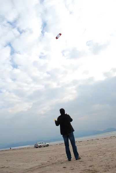 man with colorful kite against cloudy sky