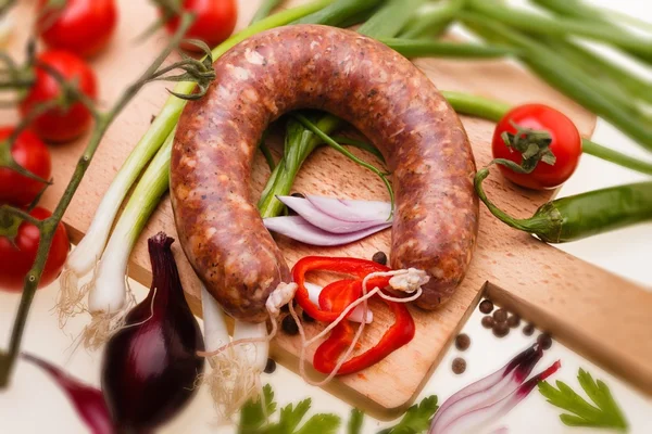 Salchicha cruda con verduras sobre tabla de madera — Foto de Stock