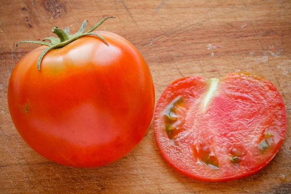 Tomate fresco na placa de corte de madeira — Fotografia de Stock