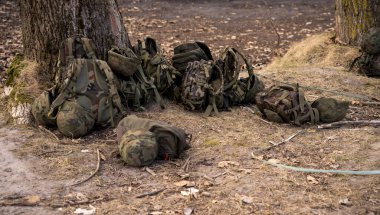 Askeri sırt çantaları ağaçların yanında yerde yatıyordu.