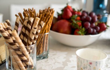 Taze ve sağlıklı yiyeceklerle dolu bir kasenin içinde tuzlu çubuklar ve birkaç tatlı tüp.
