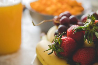 Portakal suyunun önünde muz ve üzümlü çilek.