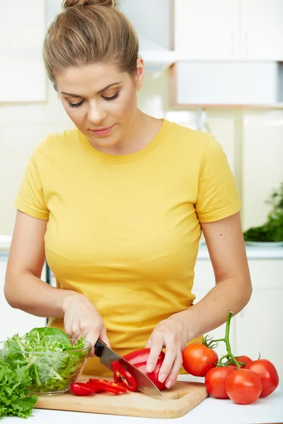 Mujer con comida vegetariana de pie contra la cocina casera —  Fotos de Stock