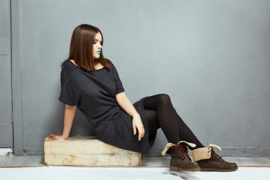 ashion tam vücut model oturma gri duvara karşı.