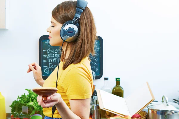 Vrouw in keuken koken met luisteren muziek — Stockfoto