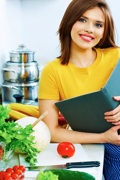 Žena vaření v kuchyni s menu knihy. — Stock fotografie