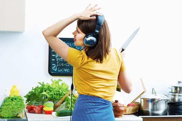 Femme cuisine dans la cuisine et écouter de la musique . — Photo