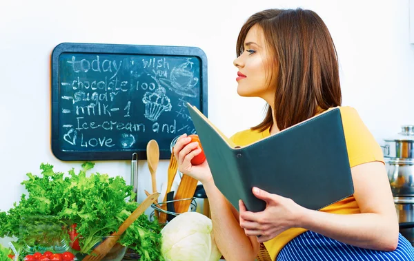 Cooking woman standing in kitchen, reed recipe from menu — Stock Photo, Image