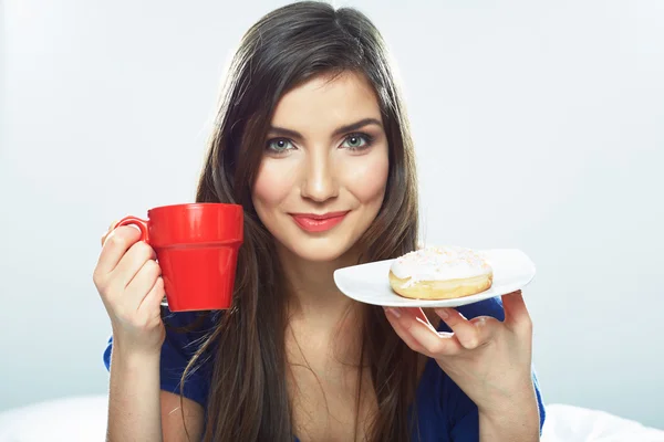 Kadın yatakta kahve fincanı ile donut yemek. — Stok fotoğraf