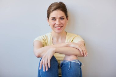 Gülümseyen dinlenen kadın sırtı duvara dönük oturuyor. Gündelik kıyafet giyen kız, izole edilmiş portre. 