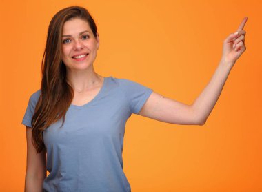 İzole edilmiş turuncu arkaplandaki fotokopi alanını gösteren mutlu kadın mavi gömlekli genç mutlu bayan..