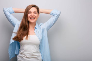 Elleri başının arkasında mutlu bir kadın. Gri duvar arka planında izole edilmiş kadın portresi. Sağlıklı dişleri olan kocaman bir gülümseme..