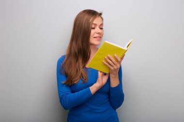 Kitap okuyan öğrenci kadın, gri duvarın yanında izole edilmiş portre..