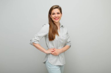 Mutlu kadın ellerini kalçasından ayırmaz, izole edilmiş kadın portresi, pantolon giymiş genç bayan ve gri gömlek.