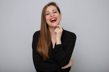 Siyah tişörtlü, gülen bir iş kadını çenesine dokunuyor. 