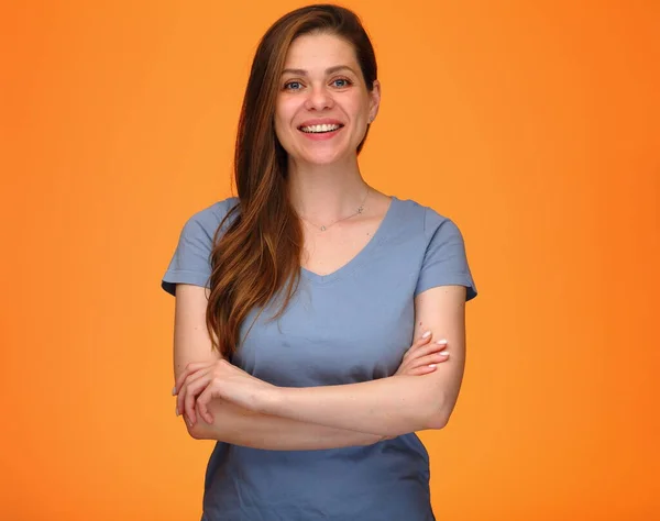 笑顔女性で青いシャツに立って腕交差孤立した肖像画上のオレンジの背景 — ストック写真