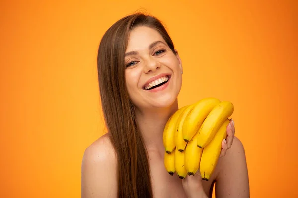 Smaling woman face and banana bunch isolated portrait on yellow orange background.