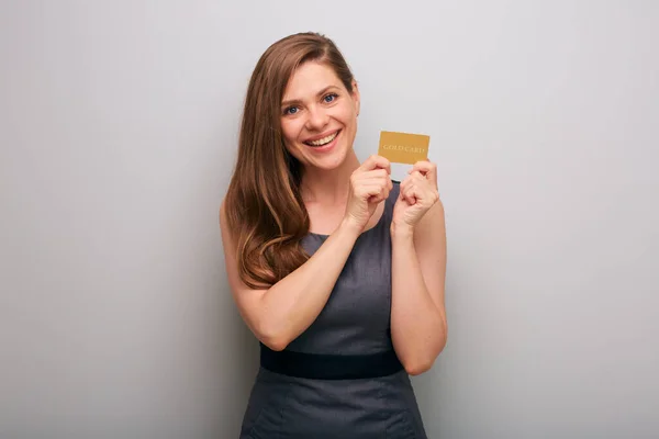 Smiling business woman in gray dress holding gold card for credit. isolated female business person portrait.