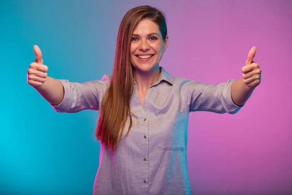 Smiling woman shows thumbs up, portrait with neon lights colors effect. Female model on neon background