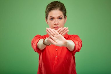 Tecrit edilmiş ciddi bir kadın, dur hareketi yapıyor, yeşil arka planda bir portre..