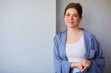 Gri duvarın yanında pijamalı, gülümseyen kadın. soyutlanmış kadın portresi.