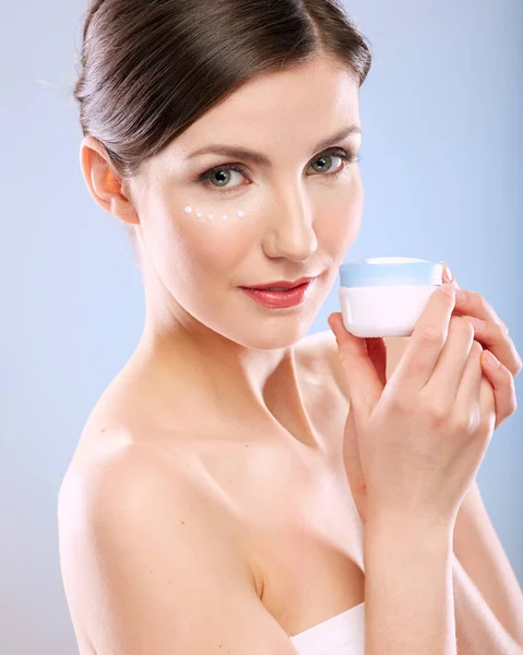 Woman with natural skin holding cream jar. Close up female face portrait.