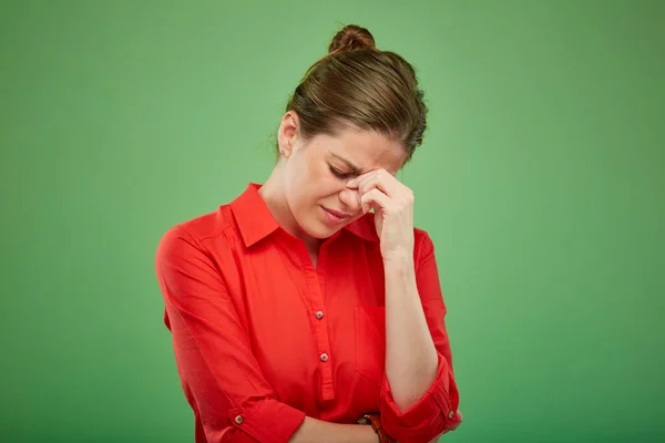 頭痛のある女性は鼻に触れ赤いシャツ緑の背景に孤立した女性の肖像画 — ストック写真