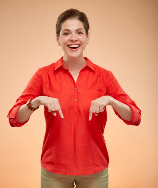 Kırmızı tişörtlü gülümseyen genç bayan parmaklarını aşağıya doğru gösteriyor, izole edilmiş kadın portresi..