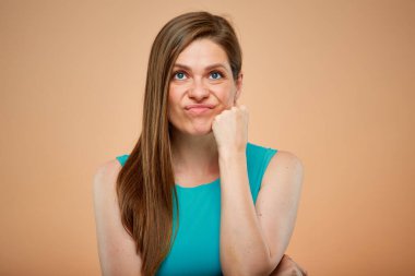 Üzüntülü, yeşil masmavi elbiseli kadın şeftali rengi arka planda soyutlanmış.