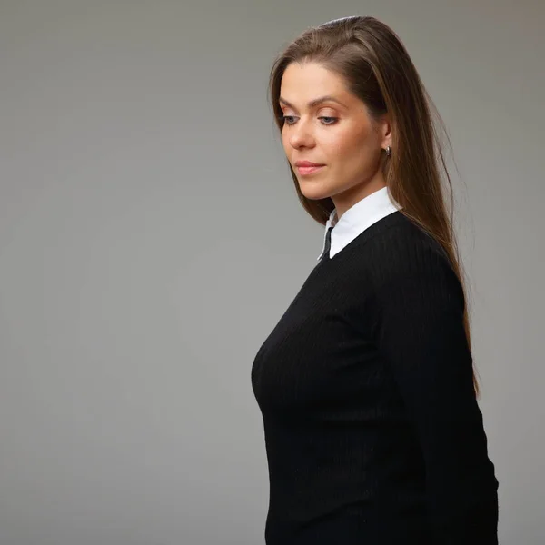 Profile of serious woman teacher in black business suit with white collar looking down, isolated female portrait.