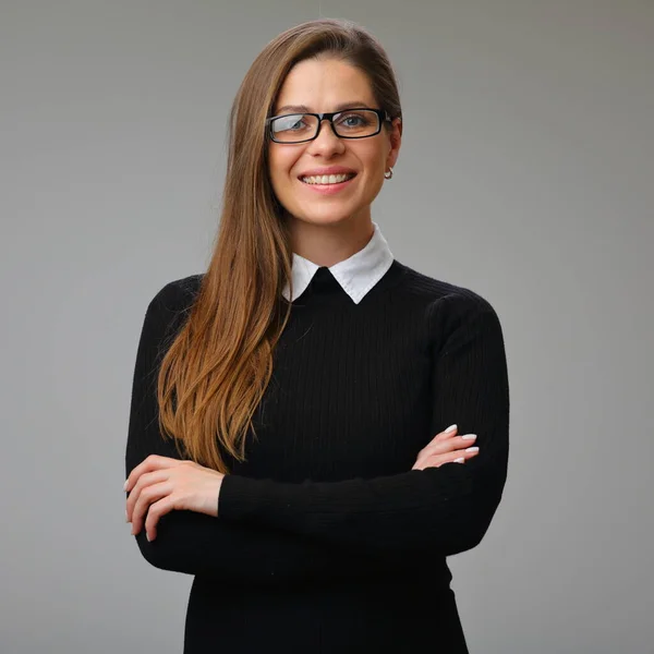 Smiling teacher or student woman in black dress with white collar wearing glasses standing with carms crossed, isolated female portrait.