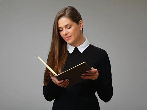 Serious woman teacher or student in black business suit with white collar  reading open book, isolated portrait of businesswoman.