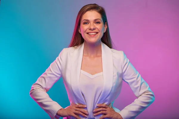 Business woman happy and smiling portrait with neon lights colors effect. Female model on neon colored background wearing white suit.