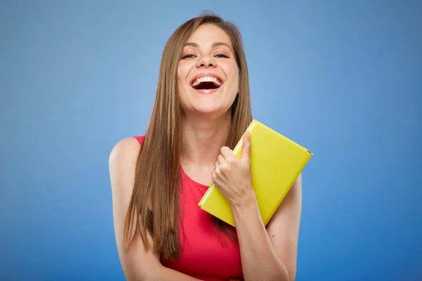Student lady in red dress holding yellow book, isolated portrait of laughing woman on blue background.