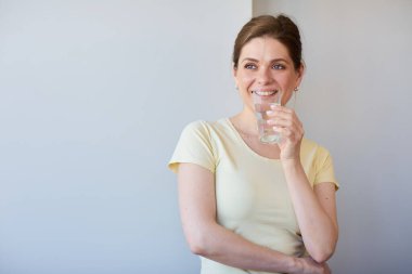 Gülümseyen ve su içen kadın gözlerini kaçırıyor. Sıradan giysili kız izole edilmiş portre..