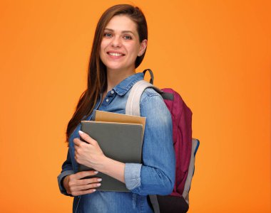 Sırt çantalı genç bir kız, portakal rengi sırtında izole edilmiş bir portre taşıyor..