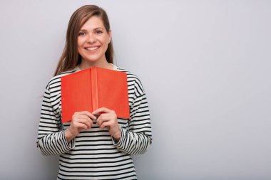 Gülümseyen mutlu genç bayan öğretmen elinde kırmızı açık kitap portresi tutuyor.  