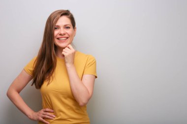 Kameraya bakıp çenesine dokunan düşünceli bir kadın. Sarı gömlekli kadın portresi.