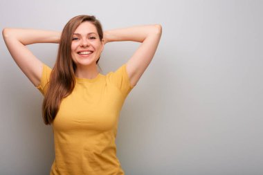 Elleri başının arkasında mutlu bir kadın. Gri duvar arka planında izole edilmiş kadın portresi.