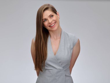 Gülümseyen mutlu kadın, elleri vücudunun arkasında duruyor. Gri arkaplanda münferit kadın portresi.