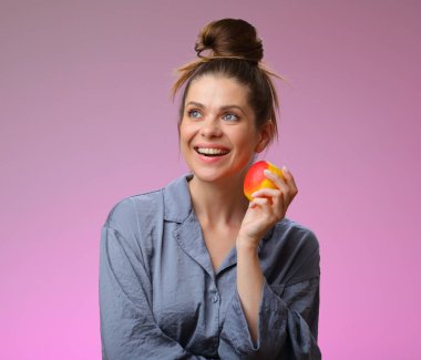 Gülümseyen kadın pijaması elmalı ve yukarı bakıyor, pembe kadın portresi üzerinde soyutlanmış.